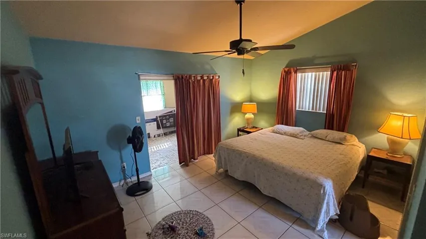 Tiled bedroom featuring vaulted ceiling and ceiling fan