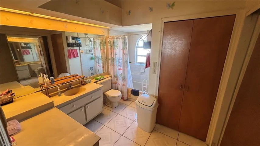 Bathroom with light tile patterned floors, vanity, and shower / bathtub combination with curtain