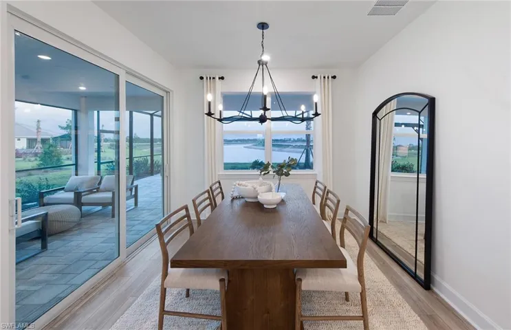 Dining area with an inviting chandelier, a water view, and light hardwood / wood-style floors