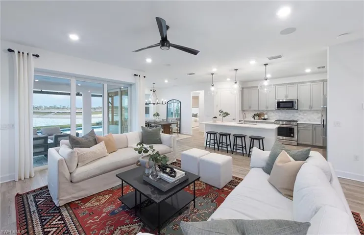 Living room with light hardwood / wood-style floors, sink, a water view, and ceiling fan with notable chandelier