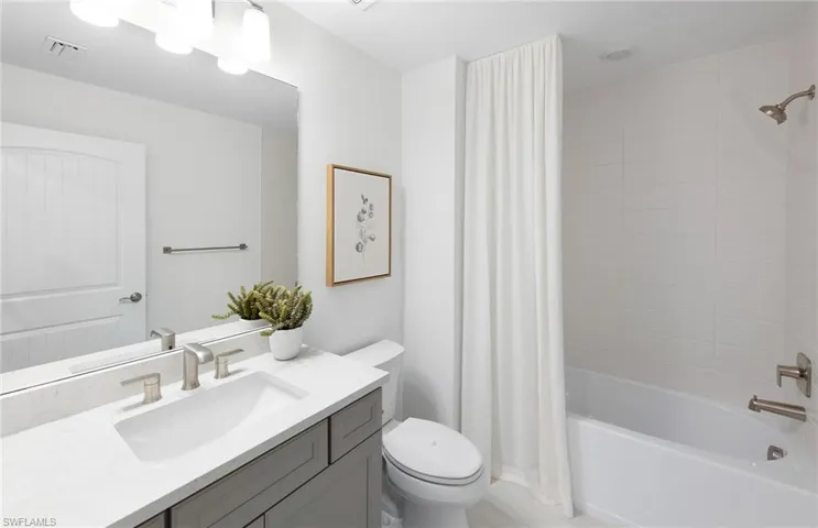 Full bathroom featuring vanity with extensive cabinet space, toilet, and shower / bath combo with shower curtain
