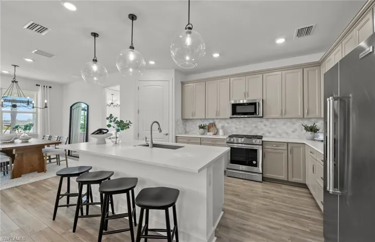 Kitchen with appliances with stainless steel finishes, sink, tasteful backsplash, and light hardwood / wood-style floors
