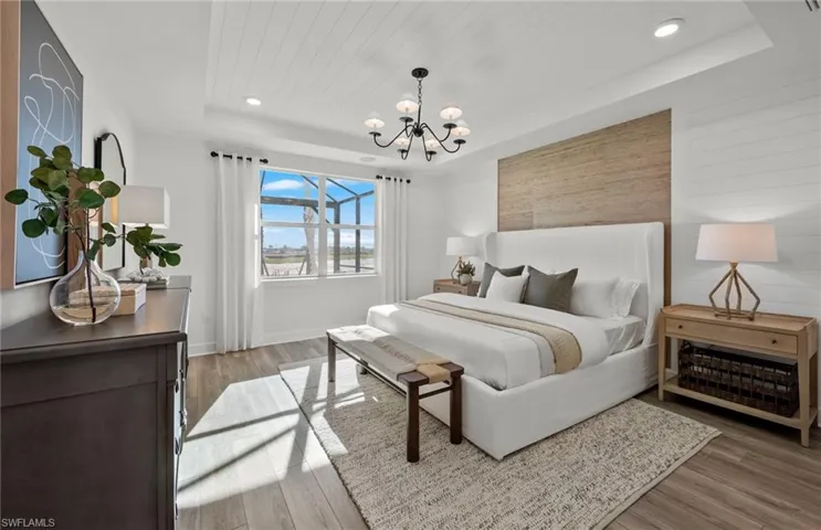 Bedroom with a notable chandelier, hardwood / wood-style flooring, and a raised ceiling
