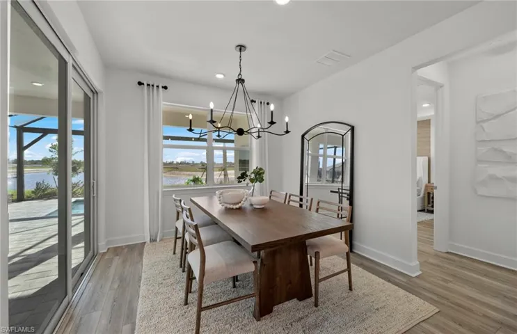 Dining area featuring an inviting chandelier, light wood-type flooring, and a water view