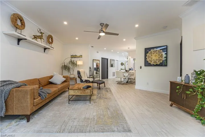 Living room featuring ornamental molding, recessed lighting, light wood-type flooring, and a ceiling fan