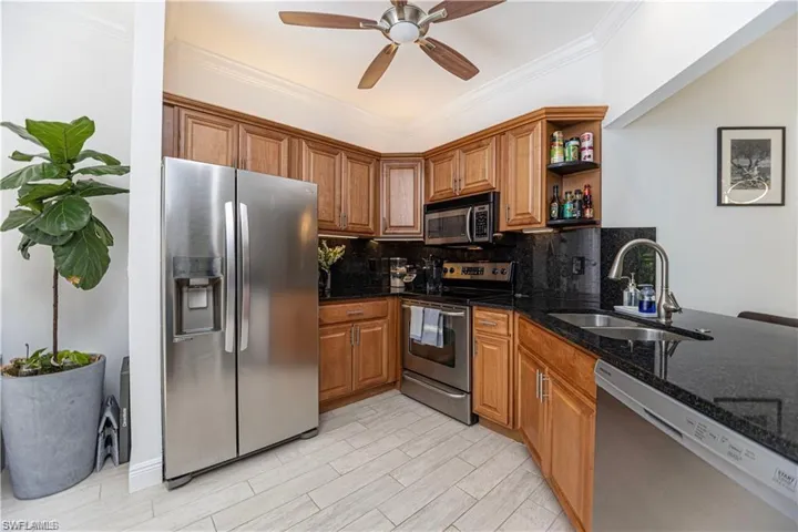 Kitchen with dark stone countertops, stainless steel appliances, brown cabinets, decorative backsplash, and open shelves