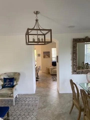 Dining area featuring crown molding, an inviting chandelier, and tile floors