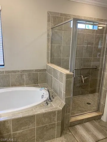 Bathroom with tile flooring, ornamental molding, and plus walk in shower