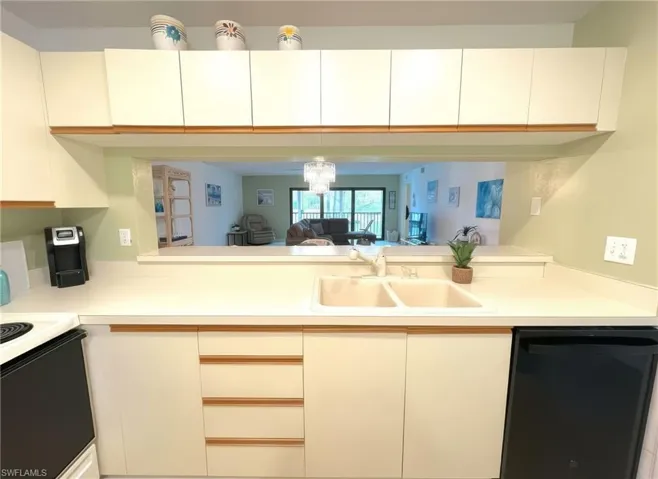 Kitchen with dishwasher, light countertops, white cabinetry, and open floor plan