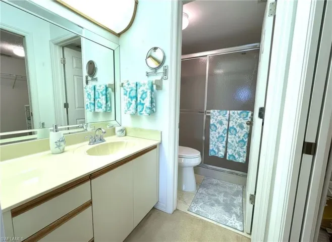 Full bath featuring vanity, a shower stall, a spacious closet, and light colored carpet