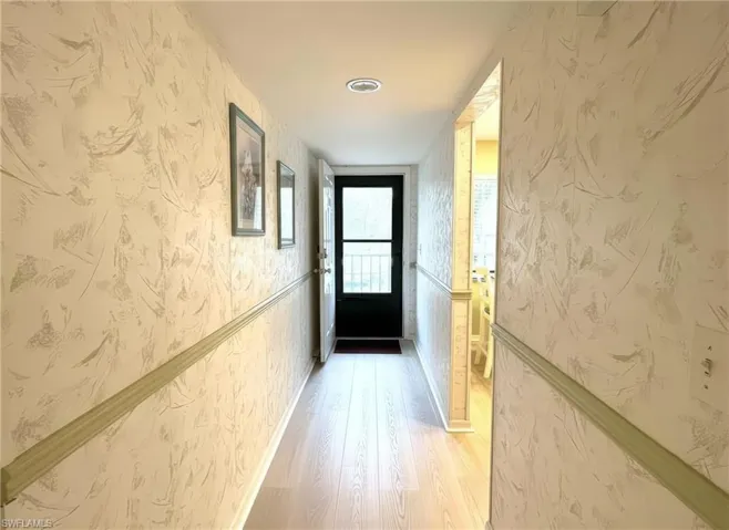 Hall with wallpapered walls and light wood-style floors