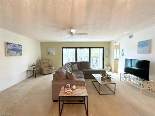 Living area featuring carpet flooring, a textured ceiling, and a ceiling fan