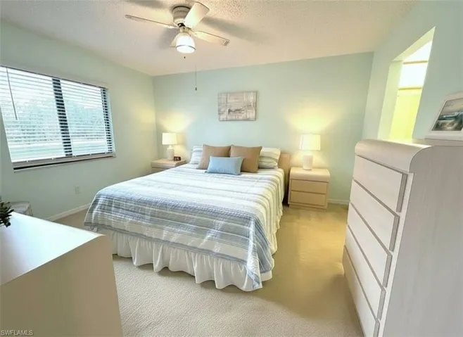 Bedroom featuring light colored carpet, a textured ceiling, and a ceiling fan