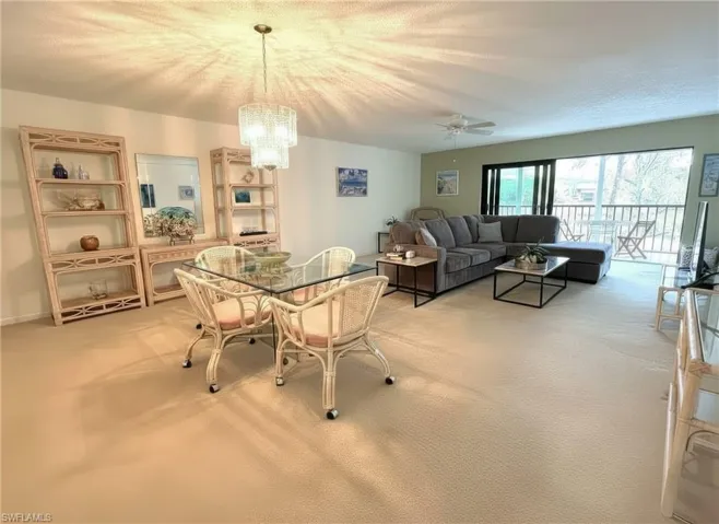 Dining space with light carpet, a chandelier, and a ceiling fan