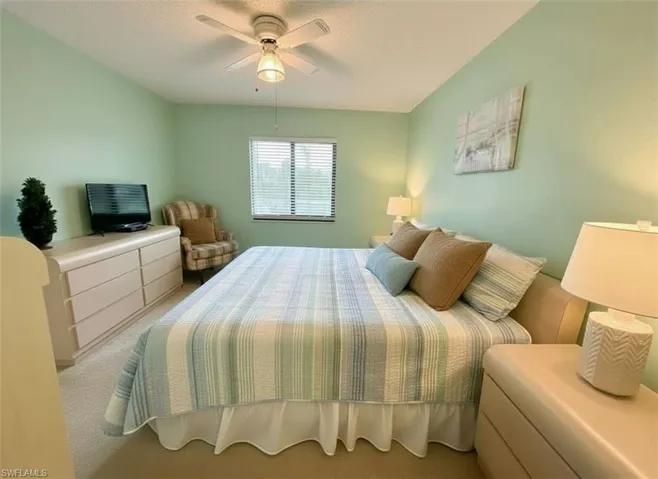Carpeted bedroom with a ceiling fan and a textured ceiling