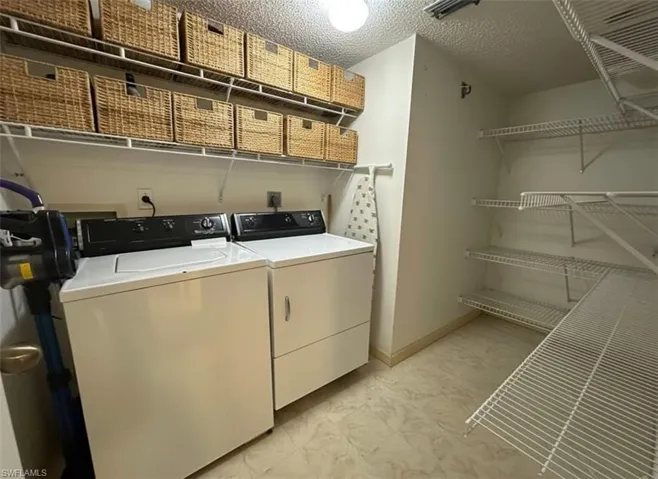 Washroom with washer and dryer, a textured ceiling, and light floors