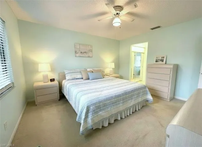 Bedroom with a textured ceiling, carpet flooring, and a ceiling fan