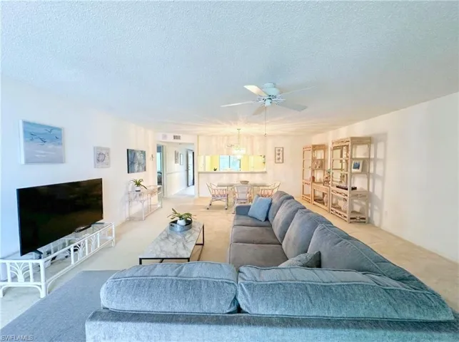 Carpeted living area with a textured ceiling and a ceiling fan