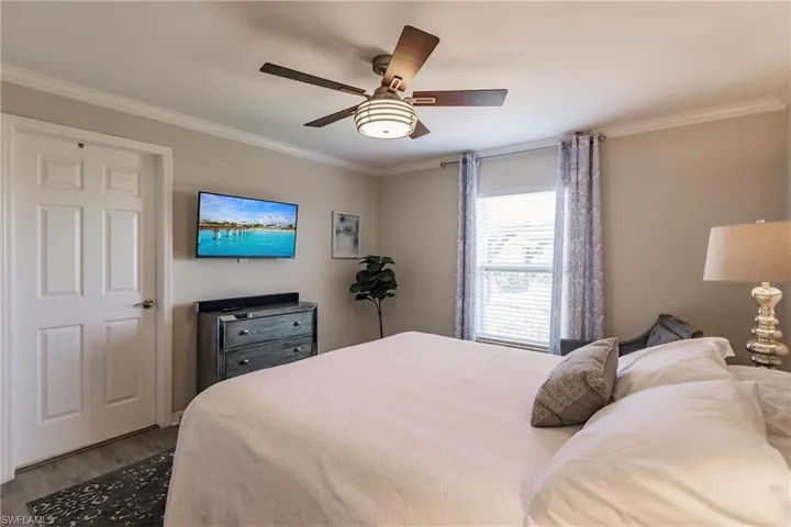 Bedroom with crown molding, ceiling fan, and hardwood / wood-style floors