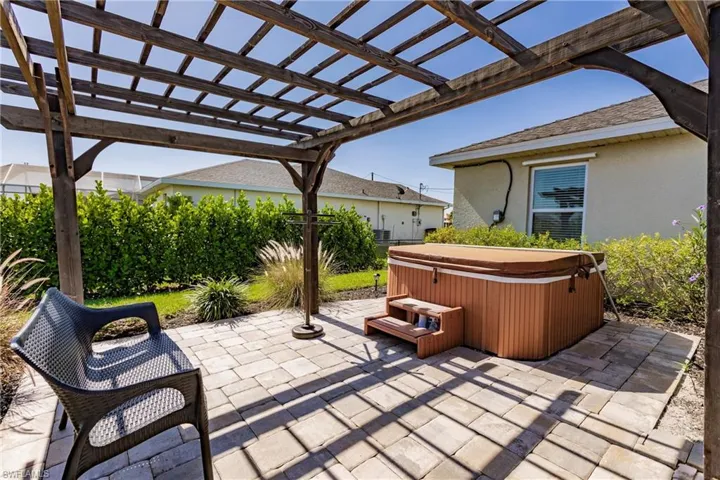 View of patio / terrace with a hot tub and a pergola