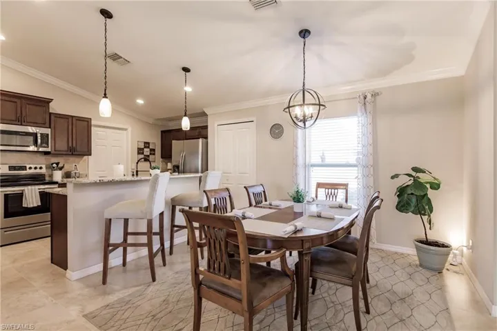 Dining room featuring ornamental molding, lofted ceiling, light tile flooring, and a chandelier