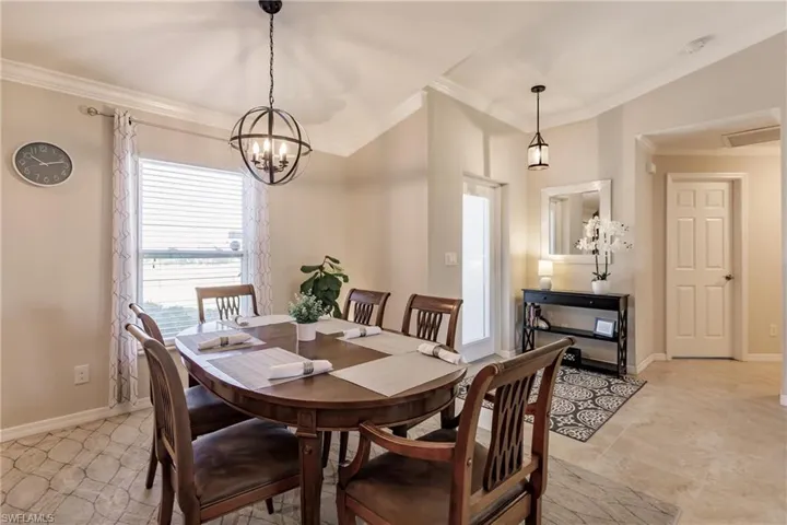 Dining area featuring crown molding, light tile flooring, and a chandelier