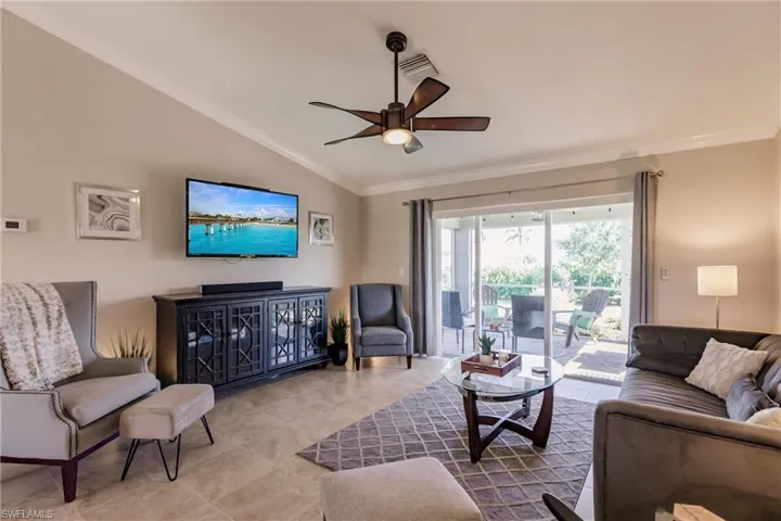 Living room with lofted ceiling, ceiling fan, tile floors, and crown molding