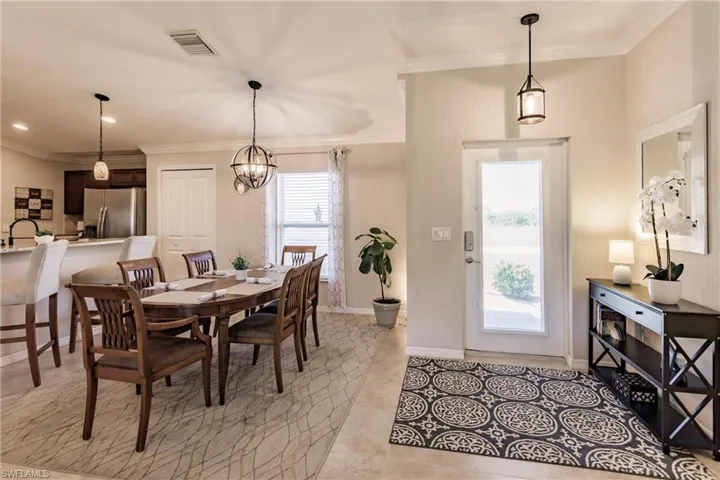 Tiled dining area with crown molding, sink, plenty of natural light, and an inviting chandelier