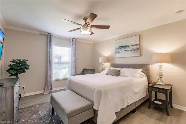 Bedroom featuring wood-type flooring, ornamental molding, and ceiling fan