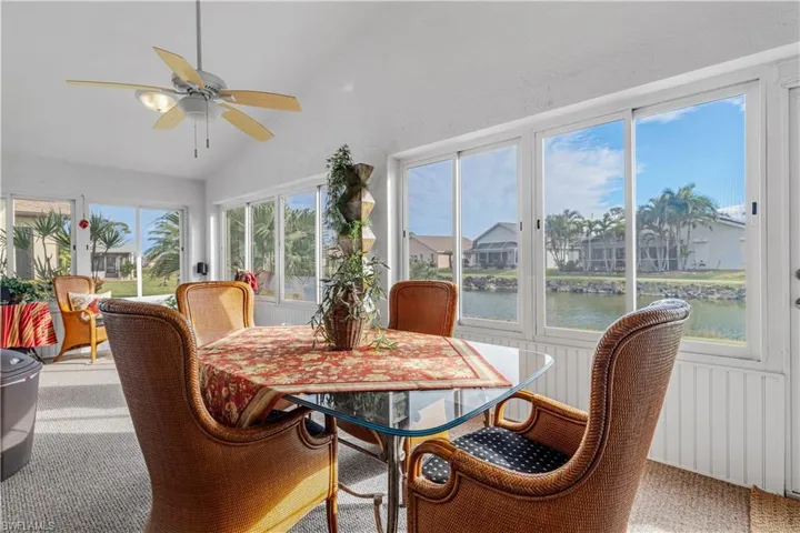 Sunroom with ceiling fan, a healthy amount of sunlight, a water view, and vaulted ceiling