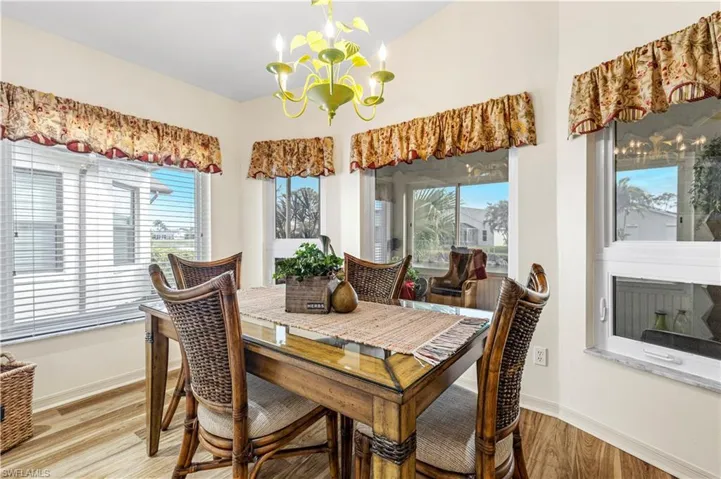 Dining space with a healthy amount of sunlight, light wood-type flooring, and an inviting chandelier