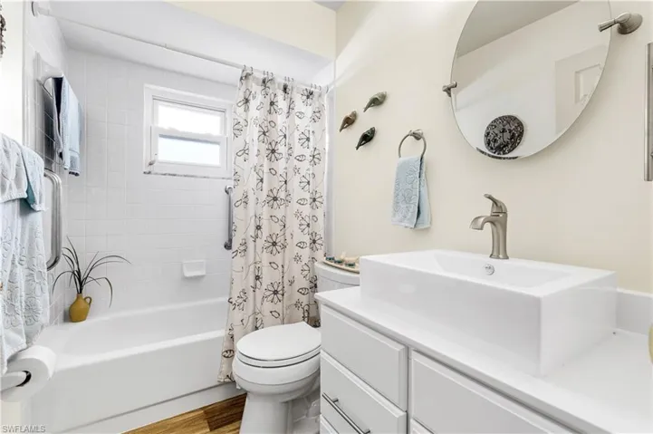 Full bathroom with toilet, shower / tub combo, hardwood / wood-style flooring, and vanity