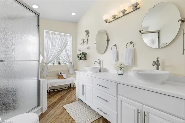Bathroom featuring a shower with shower door, hardwood / wood-style flooring, and vanity