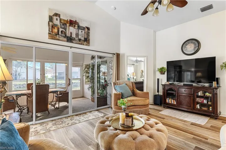 Living room featuring vaulted ceiling, ceiling fan, and light hardwood / wood-style flooring