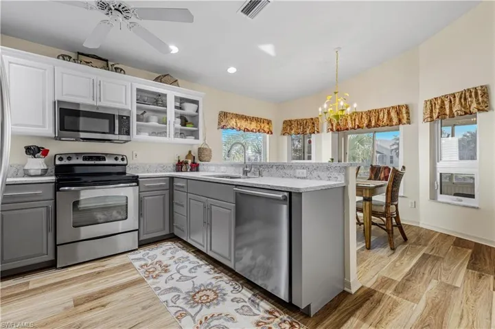 Kitchen featuring white cabinets, appliances with stainless steel finishes, and gray cabinets
