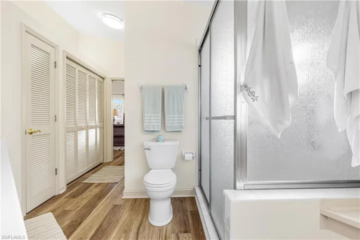 Bathroom with hardwood / wood-style floors, toilet, and walk in shower