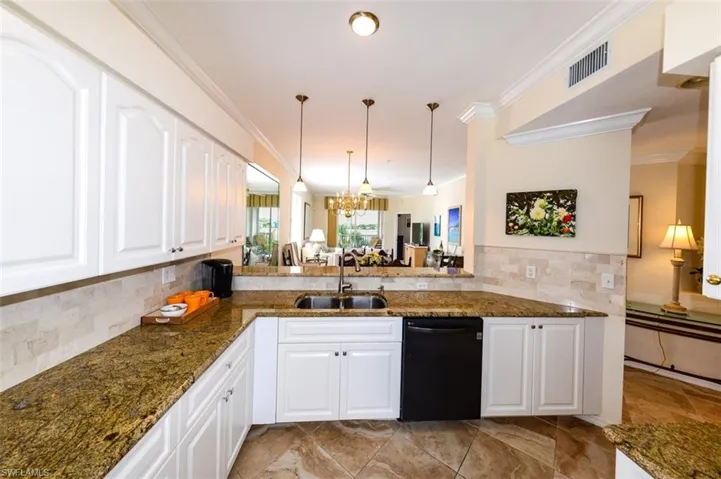 Kitchen with dark stone counters, white cabinets, backsplash, sink, and dishwasher