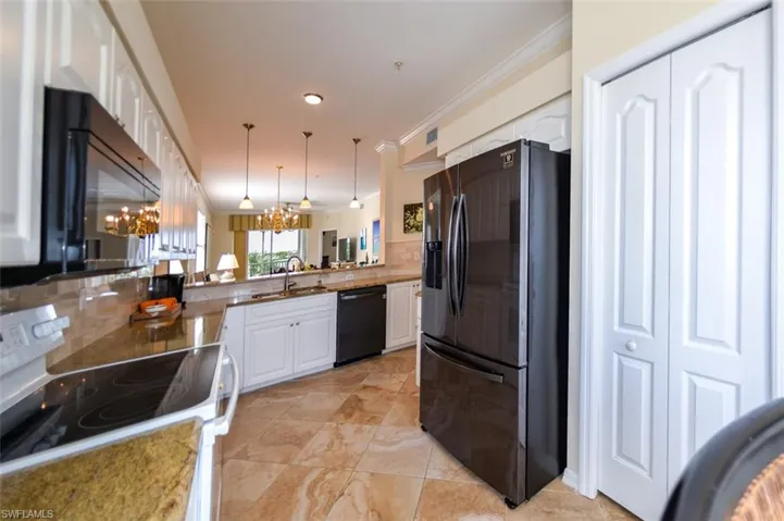 Kitchen with white cabinetry, tasteful backsplash, decorative light fixtures, and black appliances