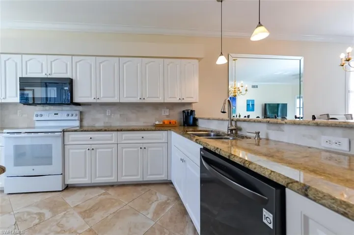 Kitchen with stone countertops, black appliances, white cabinets, sink, and pendant lighting