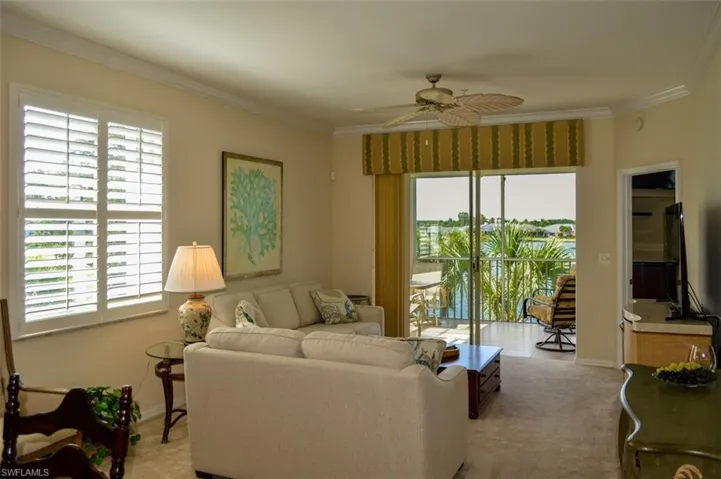 Carpeted living room with ornamental molding and ceiling fan