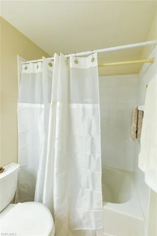 Bathroom featuring shower / bathtub combination with curtain and toilet