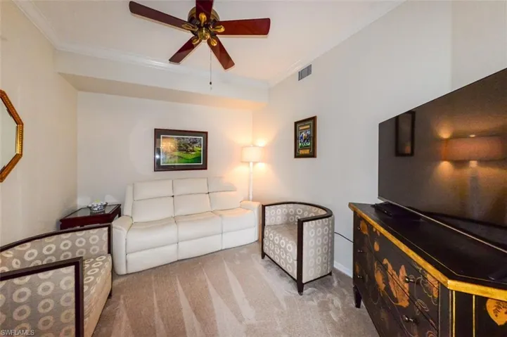 Living area featuring ceiling fan, light carpet, and ornamental molding