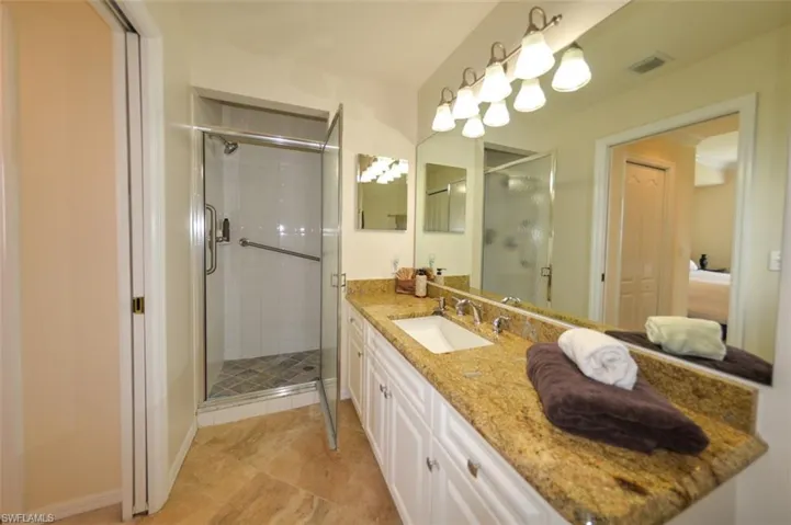 Bathroom featuring a shower with shower door, tile flooring, and double sink vanity