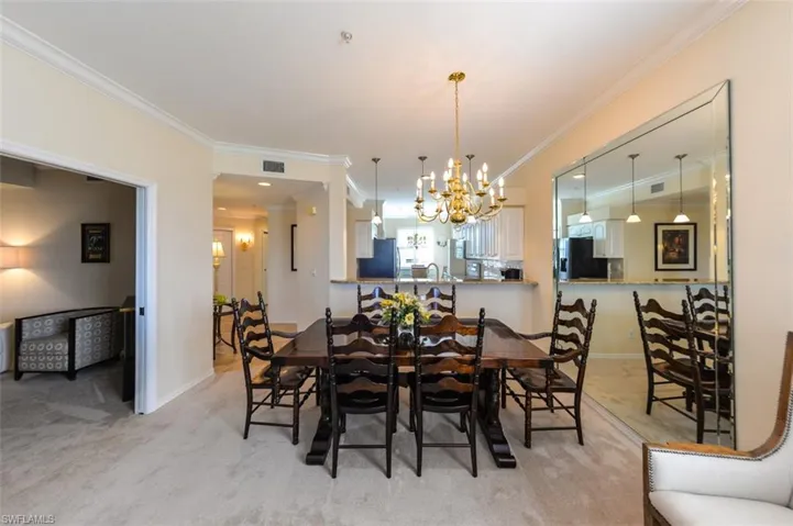 Dining area with light carpet, ornamental molding, and a chandelier