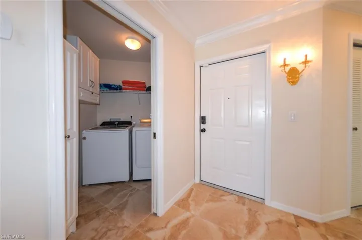 Tiled entrance foyer featuring separate washer and dryer and crown molding