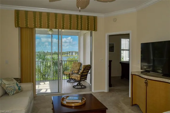 Living room with light colored carpet, ornamental molding, and ceiling fan