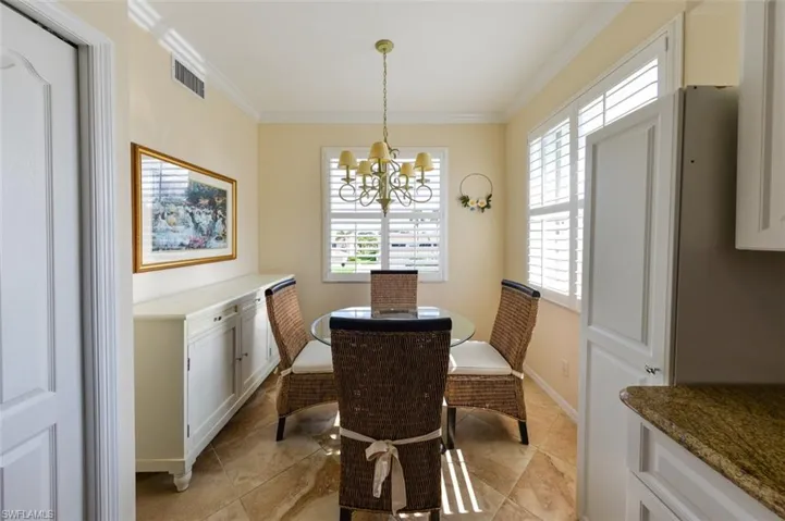 Dining area with ornamental molding, light tile flooring, and a chandelier