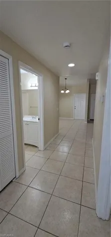Hallway with light tile patterned flooring and baseboards