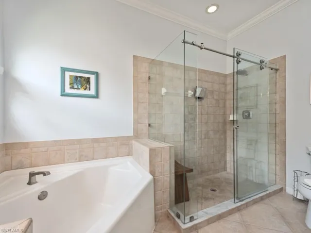 Bathroom featuring tile patterned floors, plus walk in shower, toilet, and ornamental molding