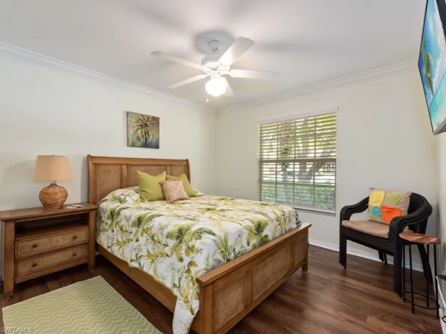 Bedroom featuring ceiling fan, crown molding, and dark hardwood / wood-style flooring